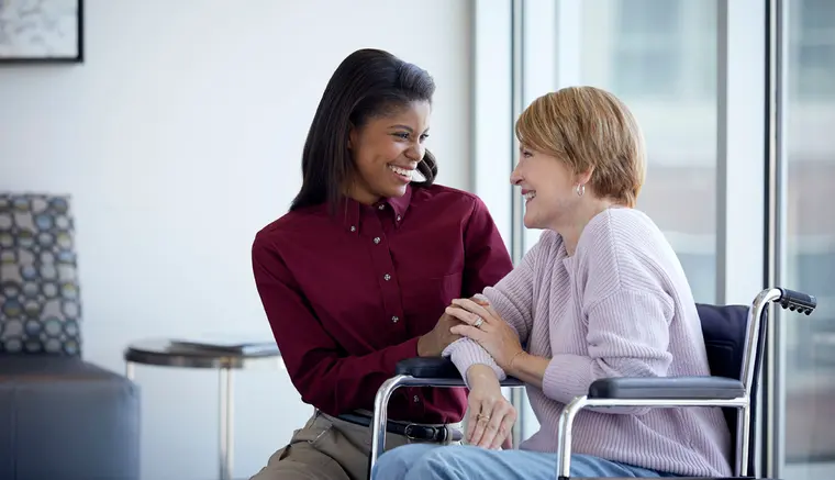 Patient transporter sharing a laugh with a patient in a wheelchair