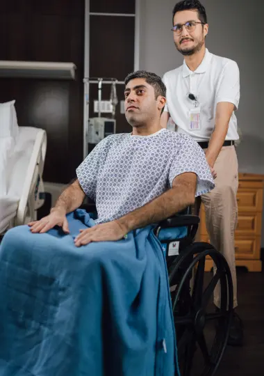 Patient transporter pushing a smiling patient in a wheelchair